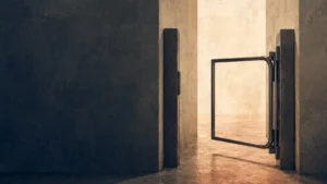 Contemporary editorial illustration of an open metal gate in a textured navy and warm parchment passage, symbolizing release, freedom, and an opened way forward.